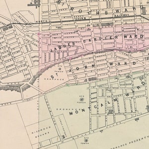 May include: A vintage map of a city with labeled wards, including Jacques Cartier Ward, John Ward, and Montreal Ward. The map shows streets, buildings, and landmarks, including a railway, a tower, and a cemetery.