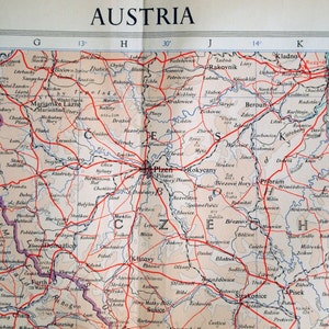 May include: A vintage map of Austria with red lines highlighting major roads and cities. The map shows the Czech Republic and parts of Germany. The map is printed on a cream-colored paper with blue and black text.