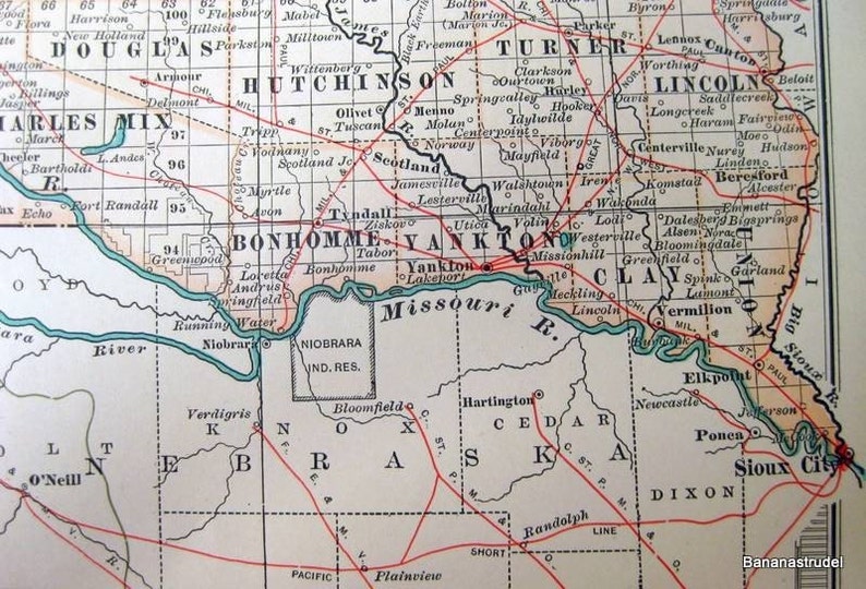 Może przedstawiać: Antyczna mapa Stan&oacute;w Zjednoczonych, przedstawiająca stany Dakota Południowa, Nebraska, Iowa i Minnesota. Mapa jest wydrukowana w czerni i bieli z czerwonymi liniami oznaczającymi granice stan&oacute;w i granicę hrabstw. Mapa zawiera nazwy miast i miasteczek, rzek i innych cech geograficznych.