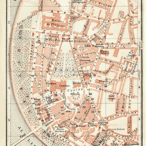 May include: An antique map of Vichy, France, depicting the city's streets, buildings, and landmarks. The map is printed in red and black ink on a white background. The map includes a key with the names of the different water sources in the city.