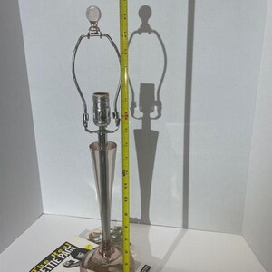 May include: A pink glass table lamp with a chrome base and a clear glass finial. The lamp is 17 inches tall and is sitting on a book titled "The Real Bettie Page".