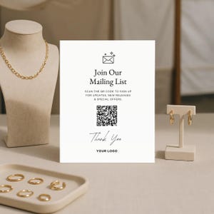 Puede incluir: Exhibici&oacute;n de joyas con un collar de cadena dorada en un maniqu&iacute;, pendientes de aro dorados y varios anillos dorados. Un letrero blanco dice "Join Our Mailing List" con un c&oacute;digo QR y "Thank You".