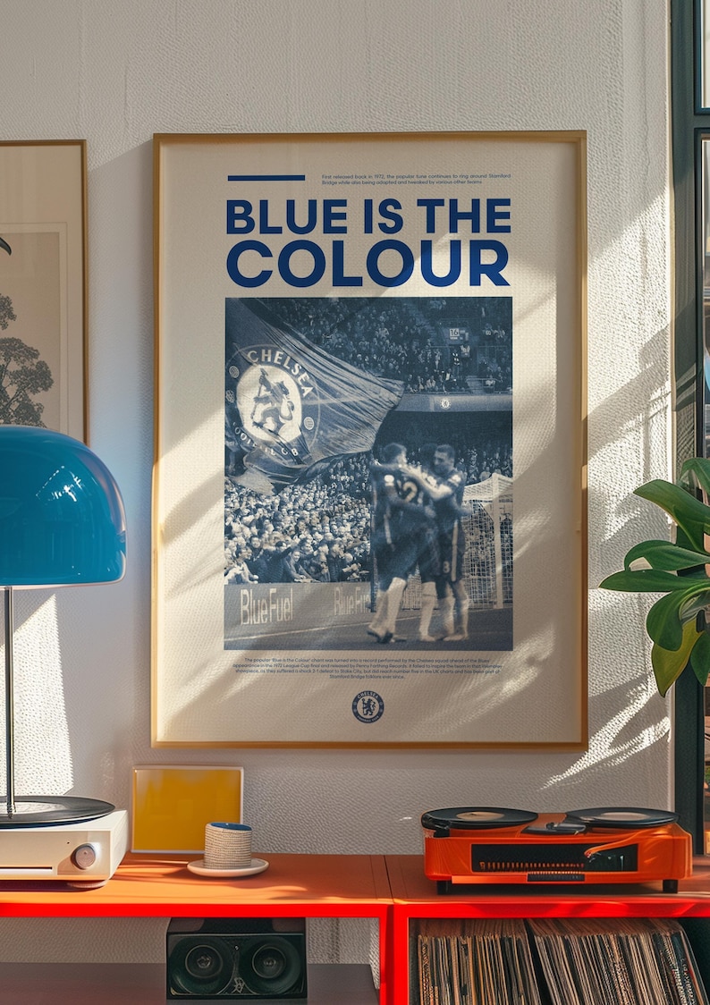 May include: A blue and white poster with the text "Blue is the Colour" and a photo of a crowd of people at a soccer game. The poster also features the Chelsea Football Club logo.