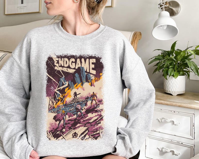 May include: A gray sweatshirt with a graphic print of a comic book cover featuring the text "ENDGAME" and characters from the Avengers movie.