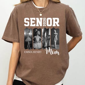 Puede incluir: Una camiseta marr&oacute;n de manga corta con el texto blanco SENIOR 2026. Debajo del texto hay cuatro paneles fotogr&aacute;ficos verticales en blanco y negro de una bailarina. El nombre EMMA HENRY y la palabra Mom est&aacute;n impresos en blanco debajo.