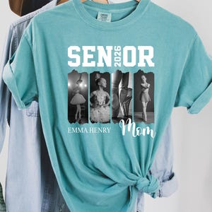 Puede incluir: Una camiseta de manga corta color verde azulado con el texto blanco SENIOR 2026 sobre cuatro paneles fotogr&aacute;ficos verticales en blanco y negro de una bailarina. Debajo de las fotos, el texto dice EMMA HENRY y Mom en letra cursiva blanca.
