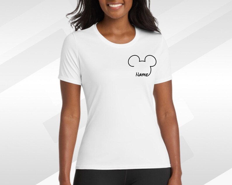 May include: White t-shirt with a black Mickey Mouse outline and the word "Name" below it. The shirt has a crew neck and short sleeves. The shirt is made of a soft, lightweight material.