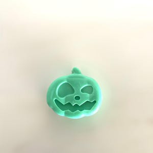 Peut inclure: Une citrouille sculptée vert clair avec un visage souriant. La citrouille a une tige et est probablement une décoration ou un objet d'artisanat d'Halloween. Le design présente de grandes découpes pour les yeux et une bouche dentelée.