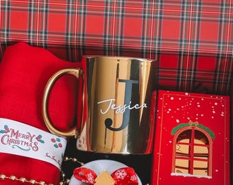May include: A gold mug with the name "Jessica" and a black "J" inside a red and plaid gift box. A red Christmas stocking with "Merry Christmas" text and a red gift box with a window design are also visible.