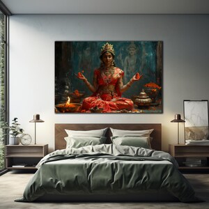 Puede incluir: Una mujer con un sari rojo y dorado se sienta en una postura meditativa con las manos levantadas, sosteniendo una flor en cada mano. Est&aacute; rodeada de flores e incienso, y se puede ver una pintura de una deidad en el fondo.