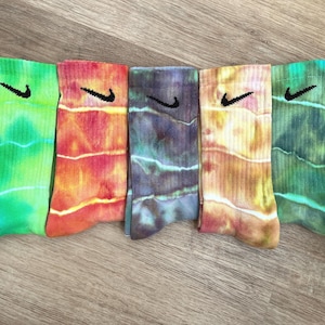 May include: Five pairs of colorful tie-dye socks with a black Nike swoosh logo on each sock.
