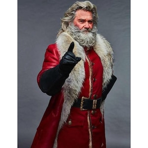 May include: A man dressed as Santa Claus wearing a red coat with a white fur trim, black leather gloves, and a black belt with gold accents. He has a long white beard and is pointing with his index finger.