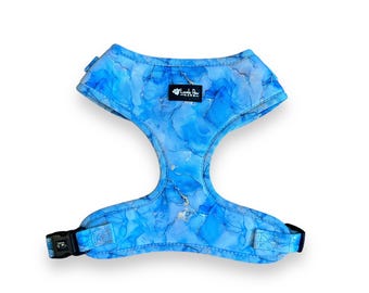 May include: A blue dog harness with a marble-like pattern and a black buckle. The harness has a small white tag with the text "Love & Paw" on it.