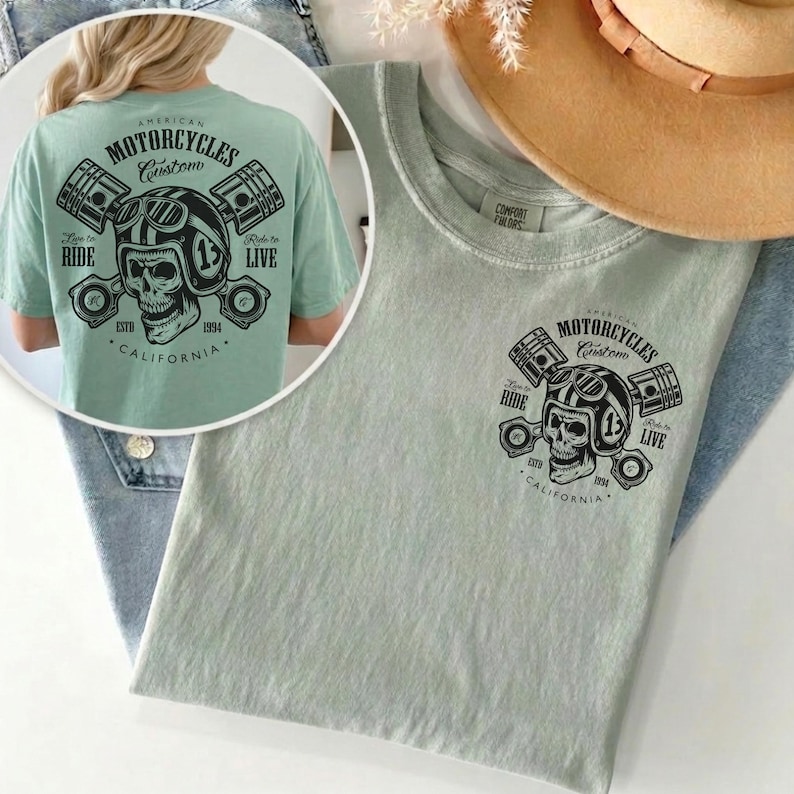 May include: A light green t-shirt featuring a graphic of a skull wearing a motorcycle helmet, pistons, and the text "AMERICAN MOTORCYCLES Custom CALIFORNIA". The shirt has the text "Ride to Live" and "Live to Ride".