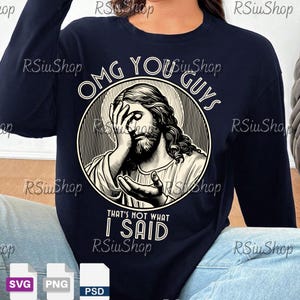May include: Navy blue long-sleeve shirt featuring a graphic of Jesus with the text "OMG YOU GUYS THAT'S NOT WHAT I SAID". The graphic is in a circular design with a halo. The shirt is a crew neck.