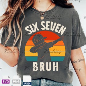 Könnte beinhalten: Dunkelgraues T-Shirt mit dem weißen Schriftzug "SIX SEVEN BRUH" und einer Silhouette eines dabenden Kindes vor einem Retro-Sonnenuntergang. Das Shirt hat einen Vintage-Look.