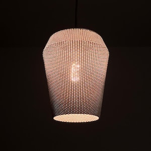 May include: A silver pendant light fixture with a round, cage-like shade made of small, evenly spaced metal circles. The light is on and illuminates the room.