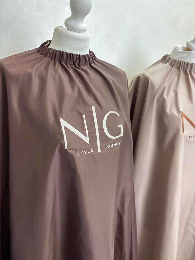 May include: Two brown and beige hair cutting capes with the text "NIG STYLE LOUNGE" on the brown cape.