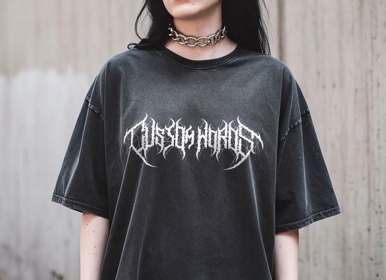 May include: Dark gray oversized t-shirt with the text "Custom Words" in a white, gothic font. The shirt has a vintage, washed appearance and short sleeves. A silver chain choker is worn around the neck.