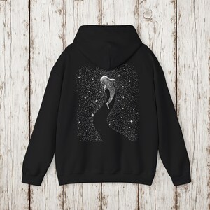 Pu&ograve; includere: Felpa con cappuccio nera con un'illustrazione bianca di uno squalo balena che nuota in un cielo stellato. Il disegno &egrave; sul retro. La felpa ha un cappuccio e maniche lunghe.