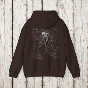 Pu&ograve; includere: Felpa con cappuccio marrone scuro con un'illustrazione bianca di uno squalo balena che nuota in un cielo stellato. Il disegno &egrave; sul retro. La felpa ha un cappuccio e una tasca frontale.