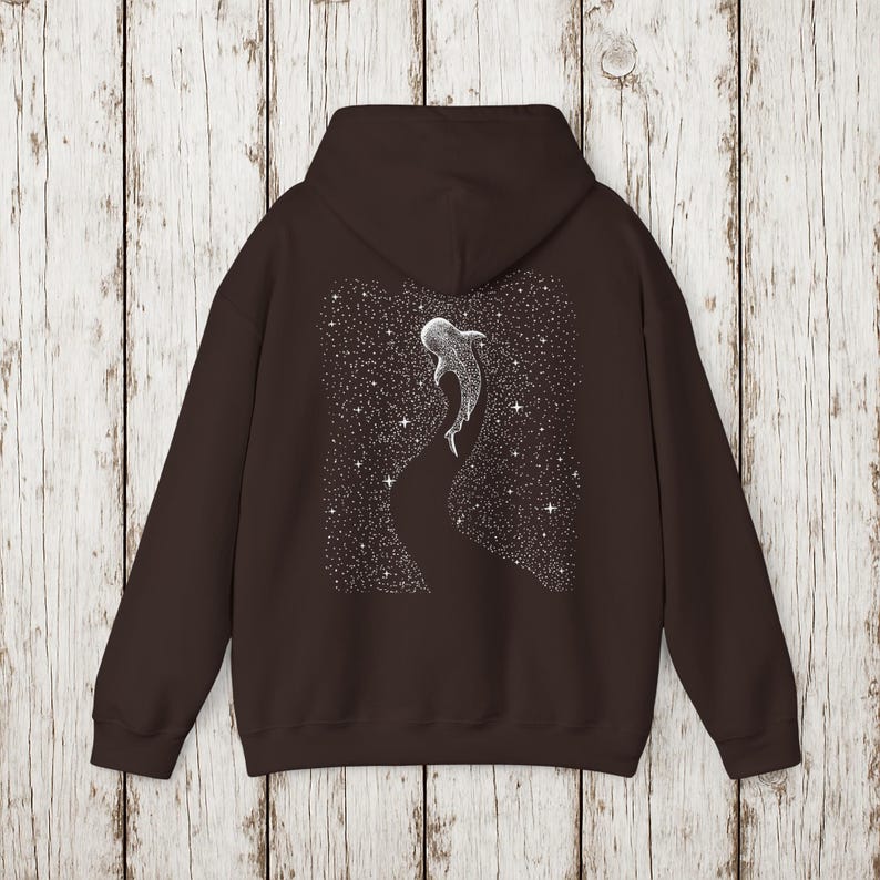 Pu&ograve; includere: Felpa con cappuccio marrone scuro con un'illustrazione bianca di uno squalo balena che nuota in un cielo stellato. Il disegno &egrave; sul retro. La felpa ha un cappuccio e una tasca frontale.