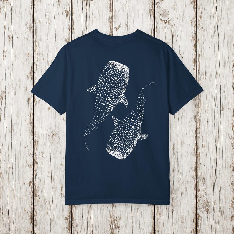 May include: Navy blue t-shirt featuring a white dotted illustration of two whale sharks. The design is on the back of the shirt. The shirt is made of a soft material.