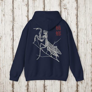 May include: Navy blue hoodie featuring a detailed white illustration of a praying mantis on the back. The design includes the Japanese characters for mantis in red. The hoodie has a drawstring hood and a kangaroo pocket.