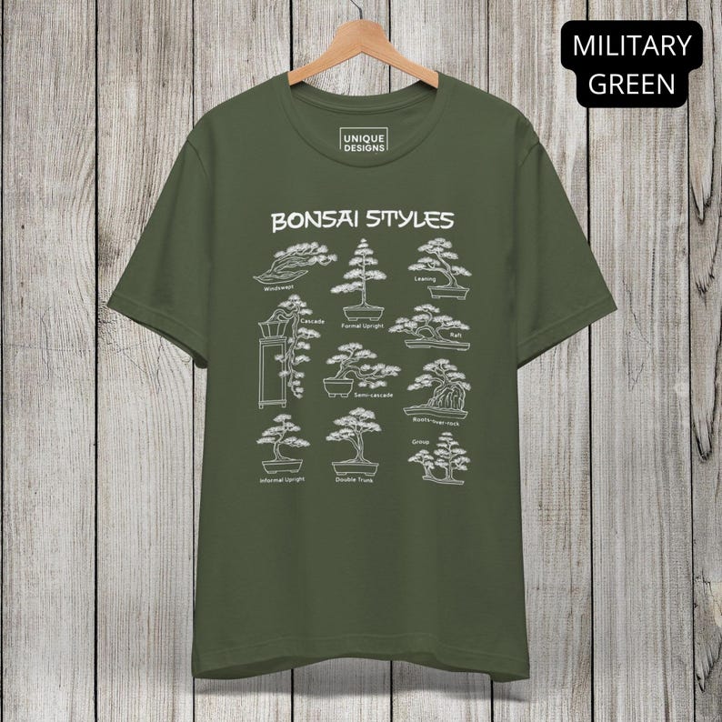 May include: A military green short-sleeve t-shirt featuring a white graphic print titled Bonsai Styles. The design displays nine distinct bonsai tree illustrations with labels including Wind-swept, Cascade, Formal Upright, Leaning, Raft, Semi-cascade, Roots-over-rock, Informal Upright, Double Trunk, and Group.