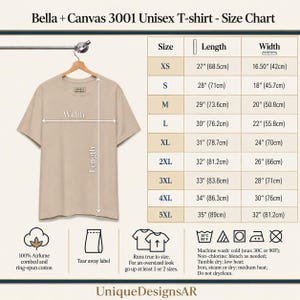 Pode incluir: Uma t-shirt bege pendurada num cabide de madeira ao lado de uma tabela de tamanhos para Bella + Canvas 3001. A tabela lista os tamanhos de XS a 5XL com comprimentos e larguras em polegadas e cent&iacute;metros. Inclui instru&ccedil;&otilde;es de cuidado.
