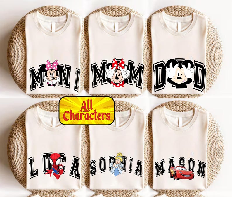 May include: Cream-colored t-shirts with various Disney character designs. The shirts feature the words "MOM", "DAD", "MINI", "LUCA", "SOPHIA", and "MASON" in black block letters. Each shirt has a different character graphic.