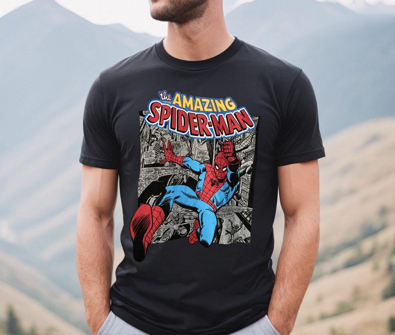 Puede incluir: Camiseta negra con una ilustraci&oacute;n de c&oacute;mic de Spider-Man. El dise&ntilde;o incluye el texto "the AMAZING SPIDER-MAN" en una fuente colorida. El superh&eacute;roe est&aacute; representado con su cl&aacute;sico traje rojo y azul.
