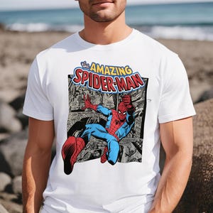 Puede incluir: Camiseta blanca con un gr&aacute;fico de c&oacute;mic de Spider-Man. El dise&ntilde;o incluye el texto "The Amazing Spider-Man" en amarillo y rojo. El superh&eacute;roe est&aacute; representado en su traje rojo y azul, en una pose din&aacute;mica.