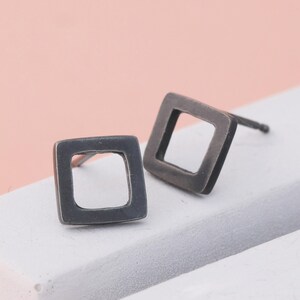 Black earrings in square shape on grey dish, sterling silver earrings
