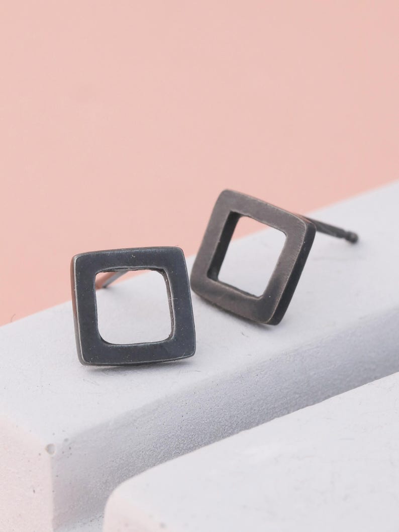 Black earrings in square shape on grey dish, sterling silver earrings