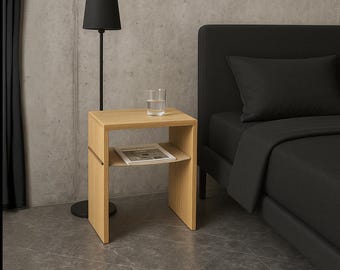 May include: A light-colored wooden nightstand featuring a square top surface and a lower shelf. The nightstand has a smooth, vertical grain finish and a simple, open-frame construction. A clear glass of water sits on the top, and a magazine rests on the shelf.