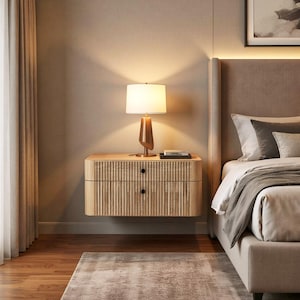 May include: A light wood floating nightstand with two drawers and a ribbed design. A lamp with a brown base and white shade sits on top. The nightstand is in a bedroom with a bed and a rug.