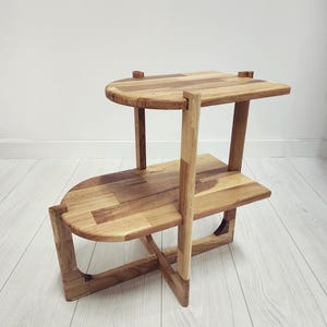 Handcrafted solid oak end table with a minimalist two-tier design. Made from natural oak wood - finished with linseed oil for a smooth - eco-friendly touch. Compact - functional, perfect for small spaces, bedrooms, living areas. Handgefertigter Nachttisch aus massivem Eichenholz mit minimalistischem zweistufigem Design. Gefertigt aus natürlicher Eiche, mit Leinöl veredelt für eine glatte, umweltfreundliche Oberfläche. Kompakt und funktional, ideal für kleine Räume, Schlafzimmer - Wohnbereiche.
