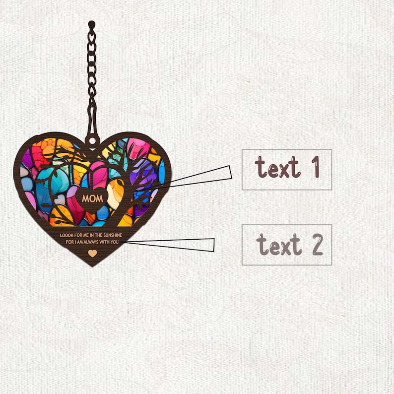 May include: A colorful stained glass heart-shaped ornament with a chain for hanging. The ornament features a tree design and the word "MOM" in the center. The text "LOOK FOR ME IN THE SUNSHINE FOR I AM ALWAYS WITH YOU" is written below the tree.