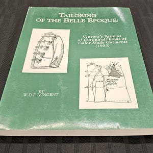 Puede incluir: Un libro verde titulado "Tailoring of the Belle Epoque: Vincent's Systems of Cutting all kinds of Tailor-Made Garments (1903)" por W.D.F. Vincent. La portada presenta una ilustración en blanco y negro de una chaqueta y un diagrama de una "Military Patrol Jacket".