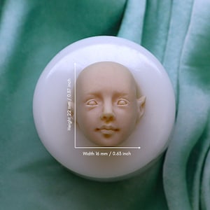 May include: A white silicone mould for making a small face sculpture. The mould is 22 mm high and 16 mm wide.