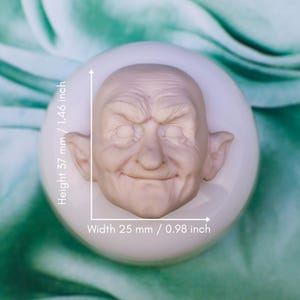 May include: A detailed, off-white silicone mold featuring a sculpted, aged face with closed eyes and a slight smile. The face measures 0.98 inches wide and 1.46 inches high. The mold is set on a white, circular base.