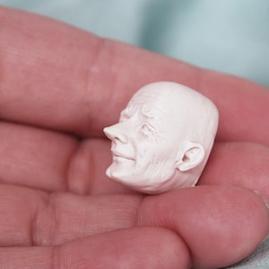 Puede incluir: Una escultura de cerámica blanca de la cabeza de una persona con rasgos faciales detallados.