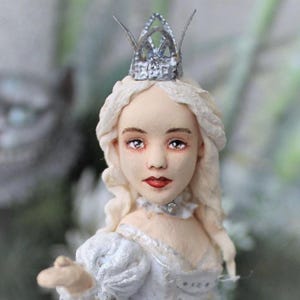May include: A porcelain doll with a white dress and a silver crown. The doll has long blonde hair and blue eyes.
