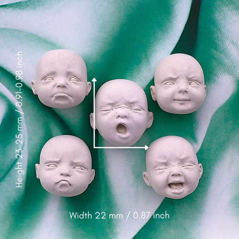 Peut inclure: Cinq petites t&ecirc;tes de poup&eacute;es non peintes avec diverses expressions faciales, dont pleurs, b&acirc;illements et sourires. Les t&ecirc;tes mesurent environ 22 mm de large et 23-25 mm de haut. Le fond est un motif abstrait vert et blanc.