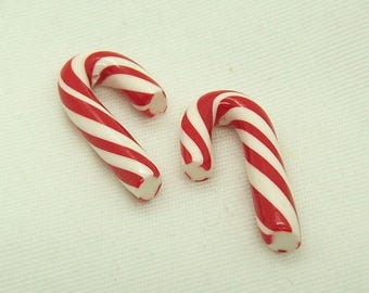 May include: Two red and white candy canes. The candy canes are made of hard candy and are shaped like a traditional candy cane.