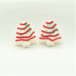 May include: A pair of white Christmas tree earrings with red and green glitter.