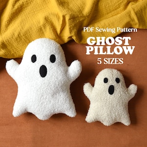 May include: Two white ghost-shaped plush pillows with black felt eyes and mouths. The text reads PDF Sewing Pattern GHOST PILLOW 5 SIZES. The pillows have a textured, fuzzy surface and are displayed against a solid orange background.