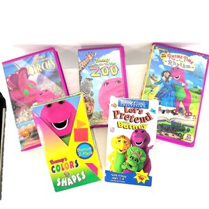 May include: A collection of Barney the Dinosaur VHS tapes and a 2-pack. Titles include "Barney's Singing Circus", "Barney Lets Go to the Zoo", "Barney's All New Rhyme Time Rhythm", and "Barney's Colors & Shapes". The tapes feature colorful graphics.