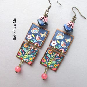 Puede incluir: Un par de pendientes colgantes con dos colgantes cuadrados con estampado floral y de mariposas en azul oscuro, acentuados por una cuenta rosa y azul en la parte superior y una peque&ntilde;a cuenta rosa en la parte inferior, con el texto Boho Style Me.